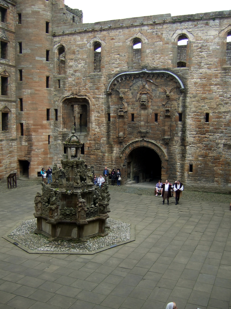 Courtyard and fountain of Linlithgow Palace, a large, ruinous and impressive royal residence of the monarchs of Scotland and birthplace of Mary, Queen of Scots, in a scenic location in a park with a pond in the historic burgh of Linlithgow.